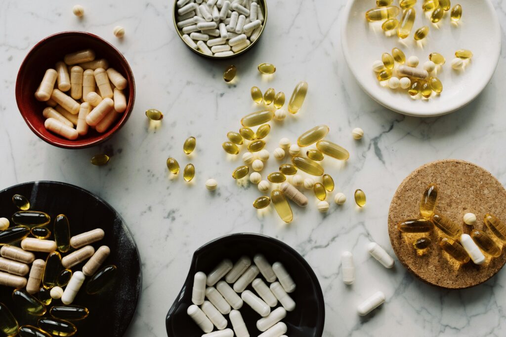 Variety of capsules and pills displayed in bowls on a marble table, ideal for healthcare concepts.