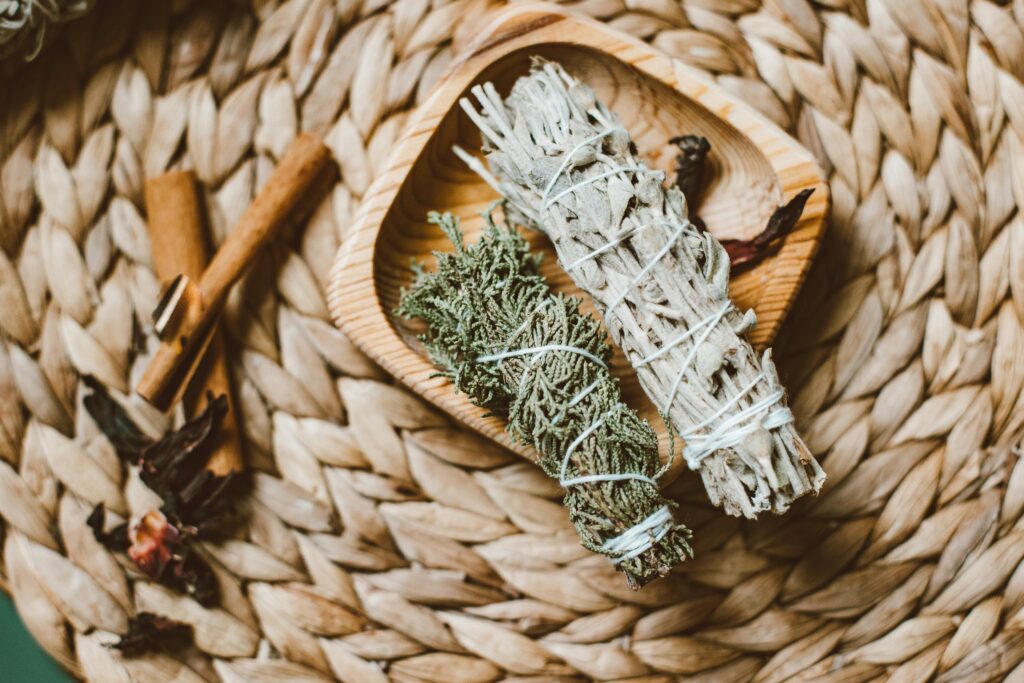 Top view of herbal incense bundles and cinnamon on woven mat, evoking a natural aromatic ritual.
